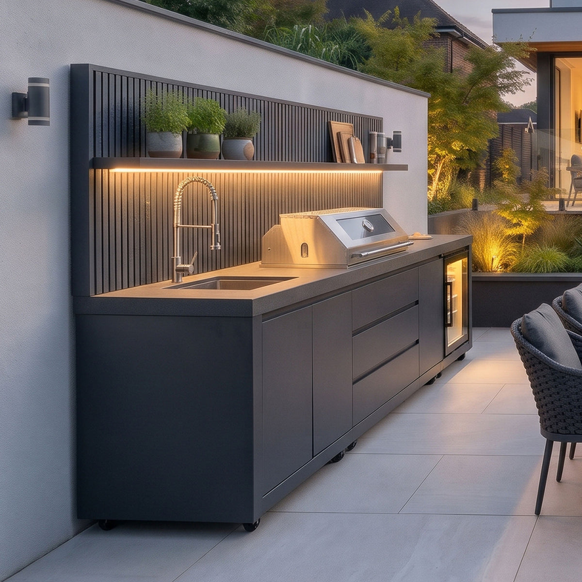 Waltons Strata Signature Outdoor Kitchen in Grey seen from the side with the shelf lit in the evening