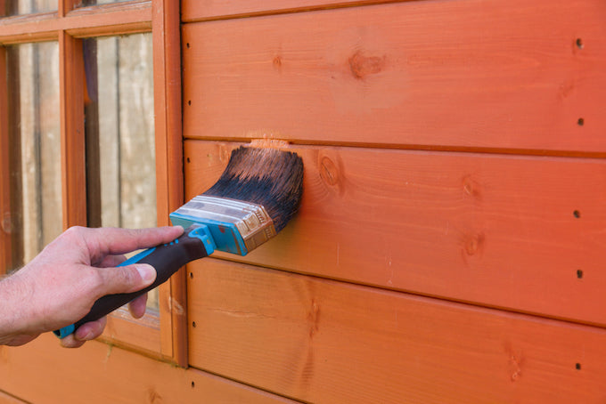 Man painting shed with wood preservative