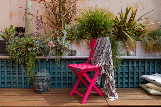 Pink chair, buddha head and a green trellis in outdoor garden Pink chair, buddha head and a green trellis in outdoor garden