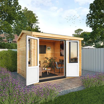 A small log cabin made from wood, with a pitched roof, double doors, in a flowery English garden on a patio with grey UPVC windows