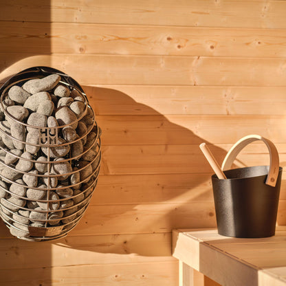 Heater and water bucket within a wooden sauna