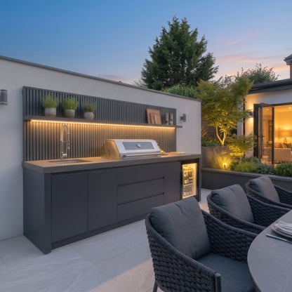Waltons Strata Signature Outdoor Kitchen in Grey with the LED shelf back wall lit at dusk
