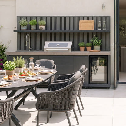 Waltons Strata Signature Outdoor Kitchen in Grey behind an outdoor dining table on a sunny terrace