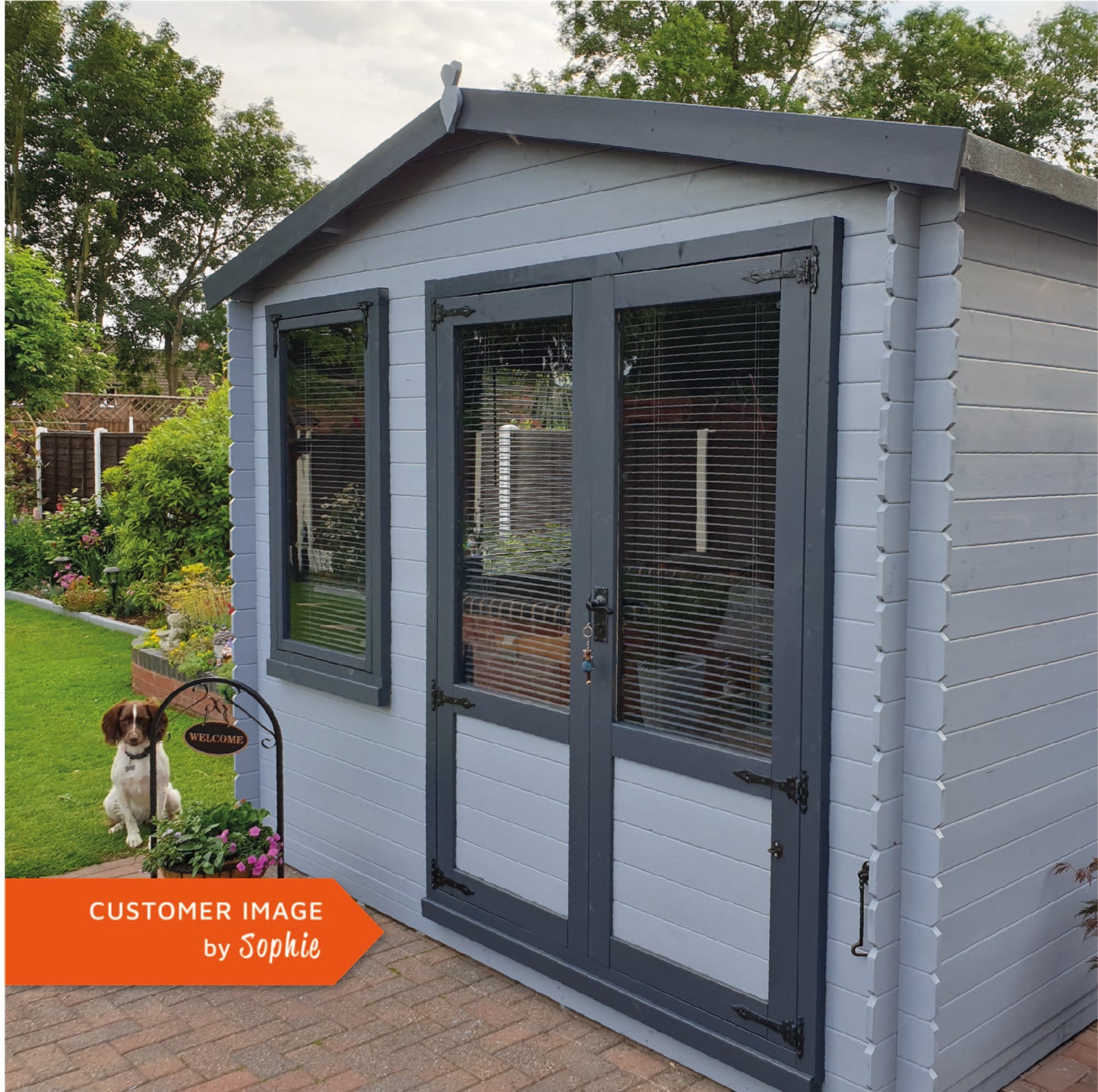 A customer image of a Traditional timber log cabin with double doors, large windows, apex roof, painted grey