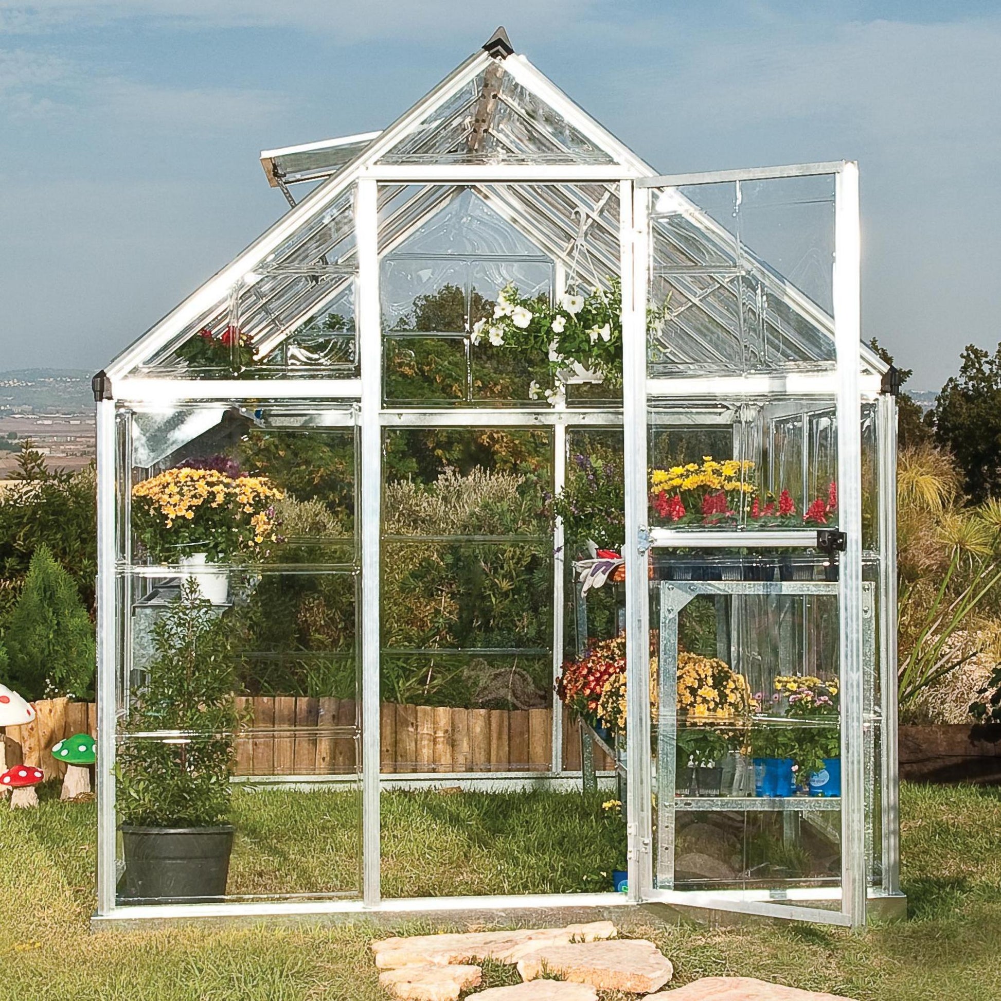 A greenhouse made from clear windows with silver metal framing