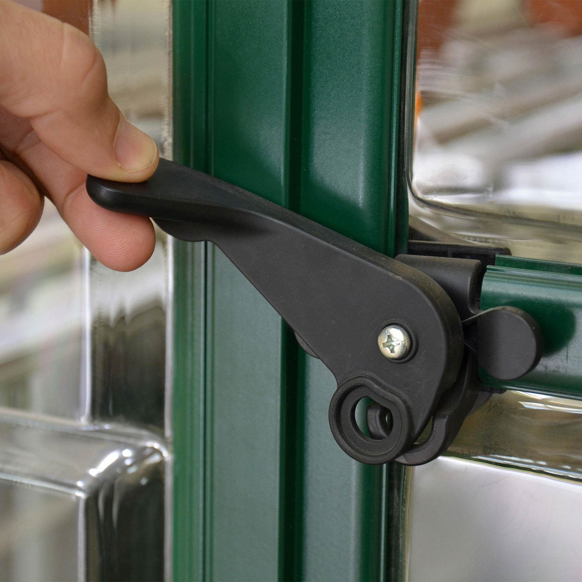 Plastic door handle on a green metal greenhouse