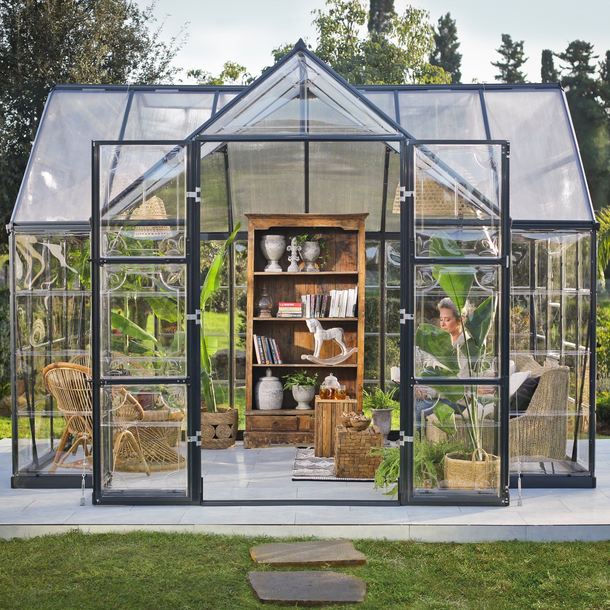 An orangery with an apex roof, made up of windows with grey metal framing